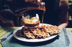 pouring syrup over waffles