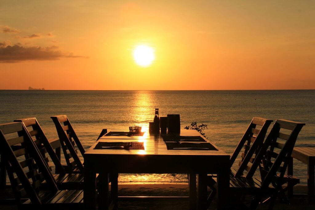 a table set in front of the water at sunset